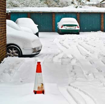 Verschneite Autos vor Garagen